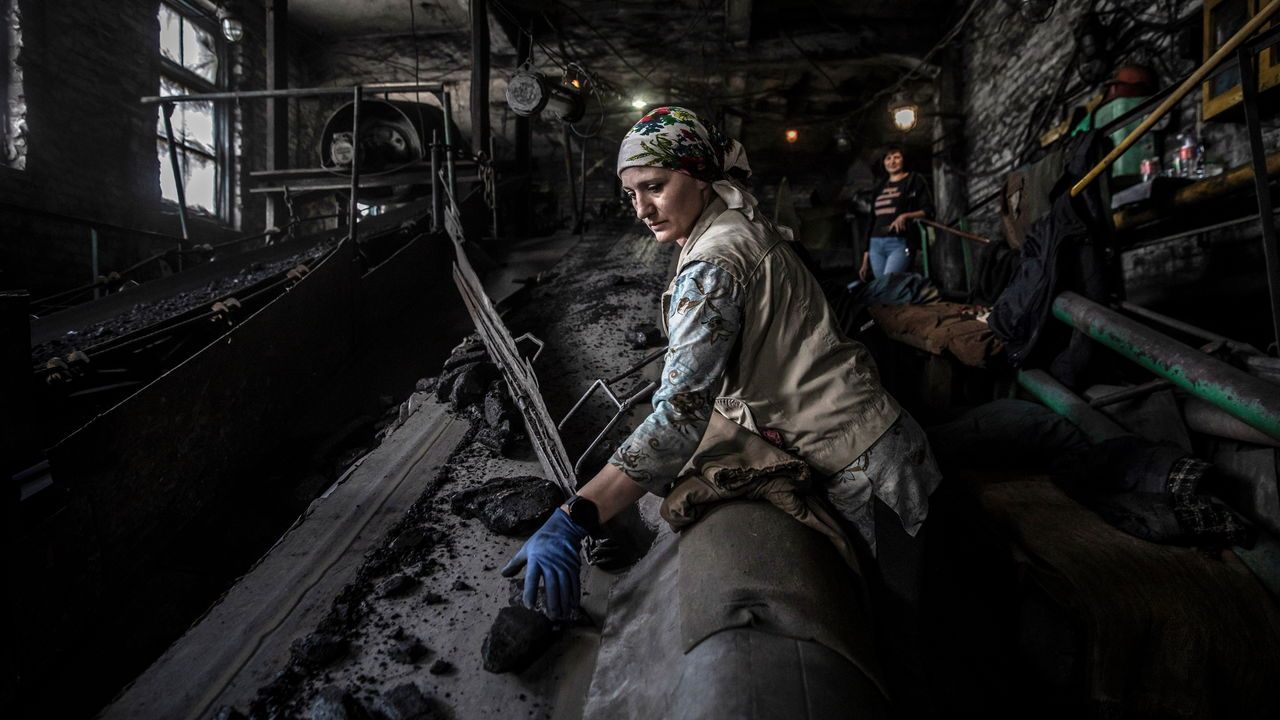 A woman sorts coal along a conveyor belt at a state-run coal mine in Donbas region, Ukraine